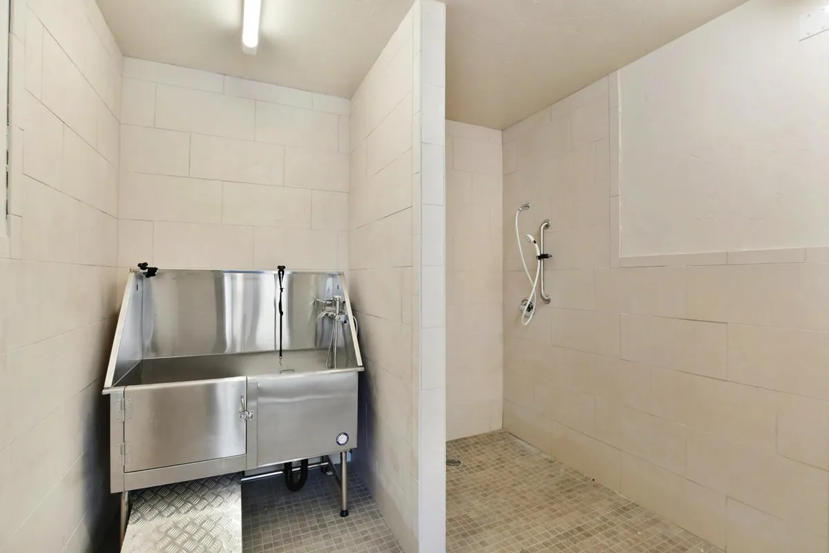 A practical, functional laundry and shower area featuring a stainless steel sink, tiled walls, and open shower space. The design is clean and modern, with a focus on utility and convenience, ideal for post-adventure clean-up or washing gear.
