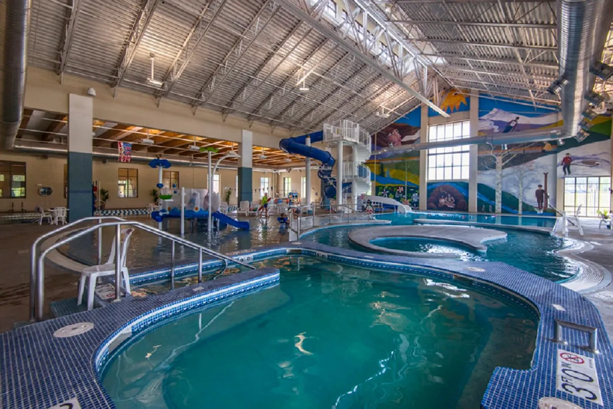 A colorful indoor recreation area showcasing water slides, a swimming pool, and a playful mural—filled with the energy of children and families enjoying water activities together.