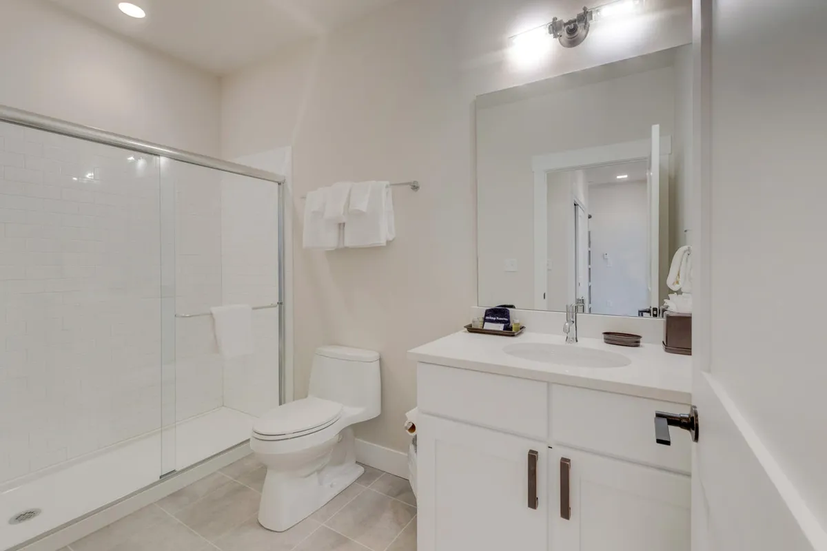A bright, modern bathroom with a glass shower enclosure, vanity with sink, neatly arranged towels, and a calming, minimalist design. The space feels private and refreshing—ideal for personal routines and self-care.